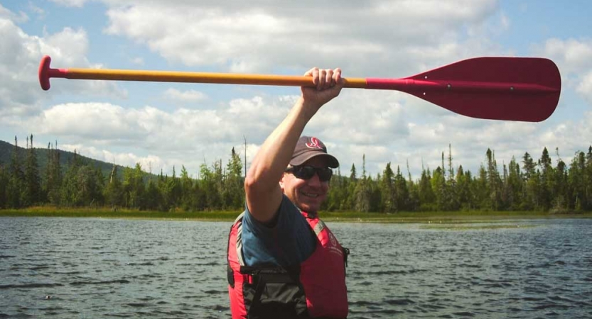 a veterans raises a paddle in the air on an outward bound expedition 